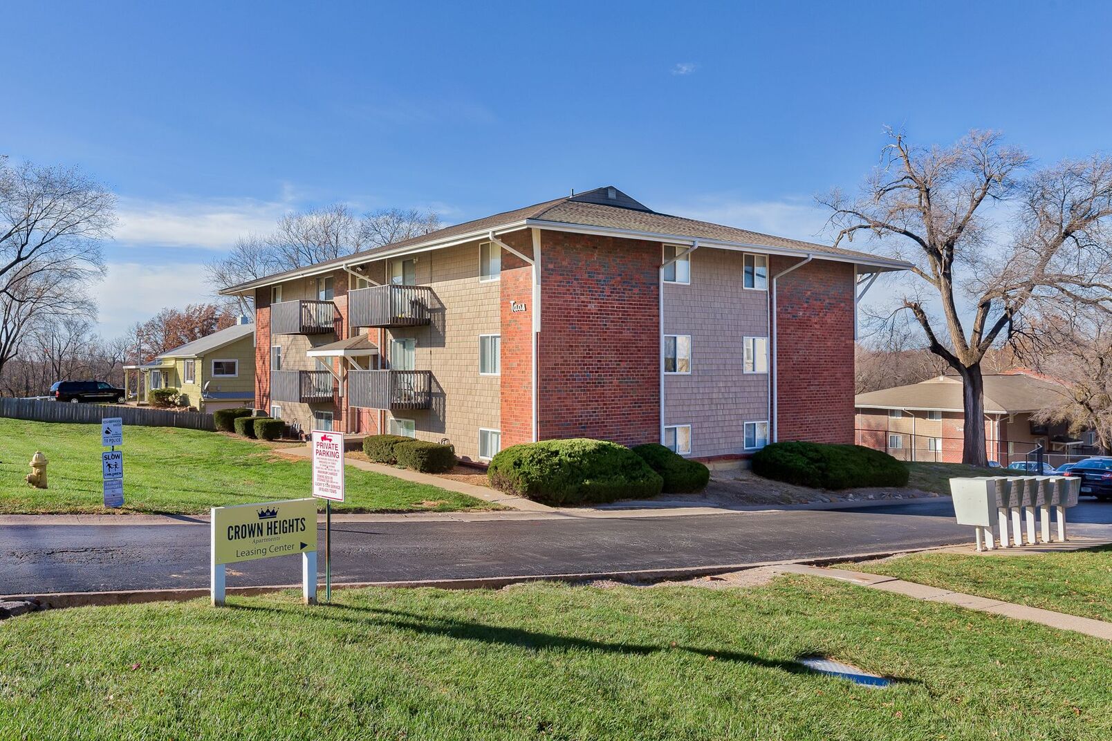 Apartment complex at street corner, featuring modern architecture and lush landscaping